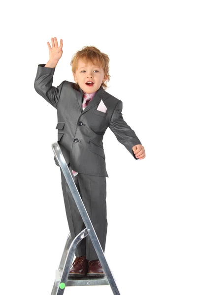 Boy in suit balances at step-ladder top — Stock Photo, Image