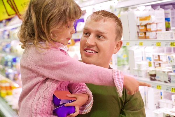 Усміхнений молодий чоловік з маленькою дівчинкою купити йогурт в супермаркеті — стокове фото