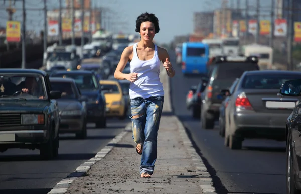 Девушка бежит по шоссе посередине города — стоковое фото