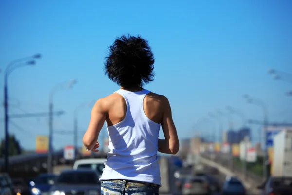 Menina vai na estrada entre carros, visão traseira no cinto — Fotografia de Stock