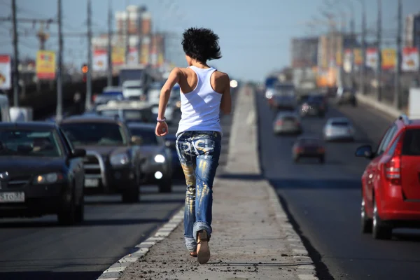 Dívka běží na dálnici uprostřed v městě — Stock fotografie