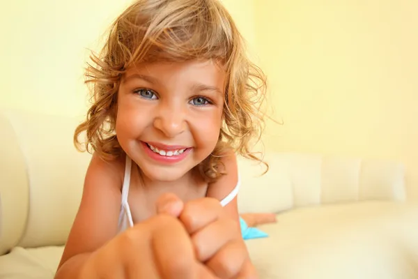 Симпатичная улыбающаяся маленькая девочка в уютной комнате, протягивает руки вперед — стоковое фото