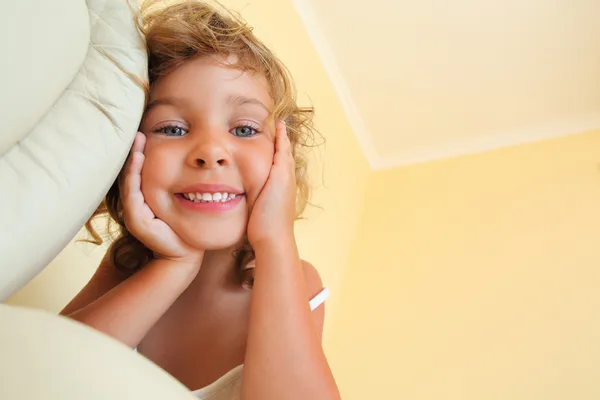 Красивая улыбчивая маленькая девочка в уютной комнате, отмахивающаяся от бела — стоковое фото