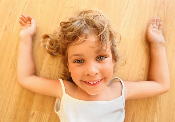 Muito sorrindo menina encontra-se no chão — Fotografia de Stock