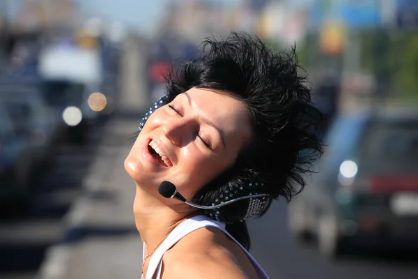 Sonriente chica en auriculares conjunto en medio de la carretera — Foto de Stock