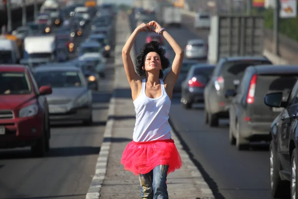 Girl in pink skirt goes on highway middle — Stock Photo, Image