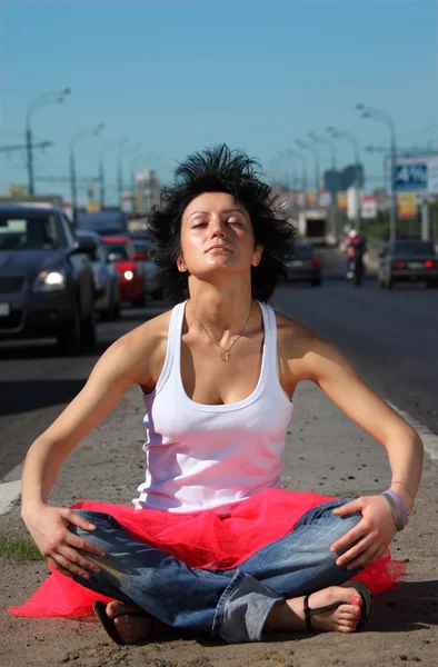 Girl in pink skirt meditates on highway middle — Stock Photo, Image