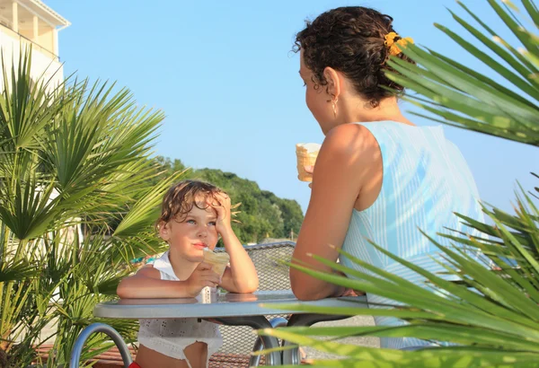 Niña y joven comen helado cerca de palmeras en res —  Fotos de Stock