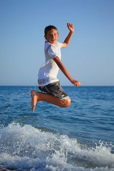 Saut adolescent garçon sur littoral — Photo