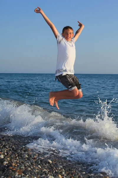 Springender Teenager am steinernen Meeresufer — Stockfoto
