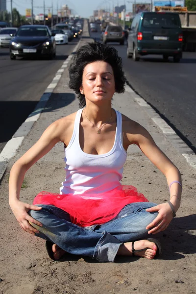 stock image Girl in pink skirt meditates on highway middle