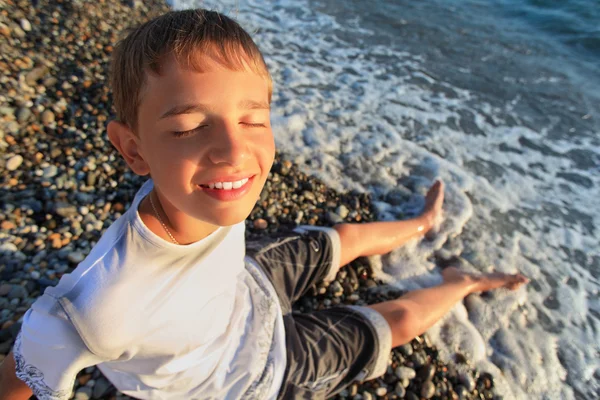 Sitting teenager boy on stone seacoast, closed eyes, wets feet i — Stock Photo, Image