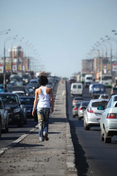 Meisje gaat op snelweg midden in de stad, uitzicht vanaf de achterkant — Stockfoto
