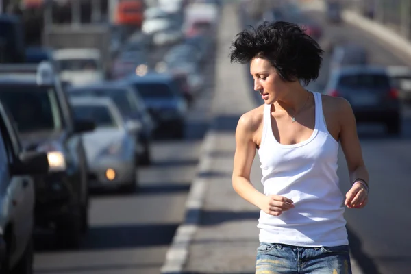 3.女孩在市中心高速公路上跑步，用皮带观看 — 图库照片