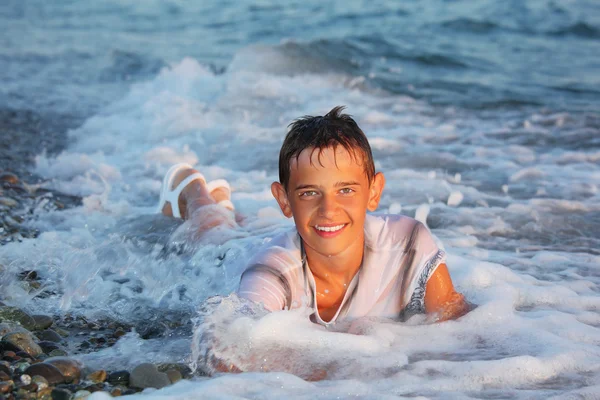 Tonåring pojke simma i kläder i havet — Stockfoto