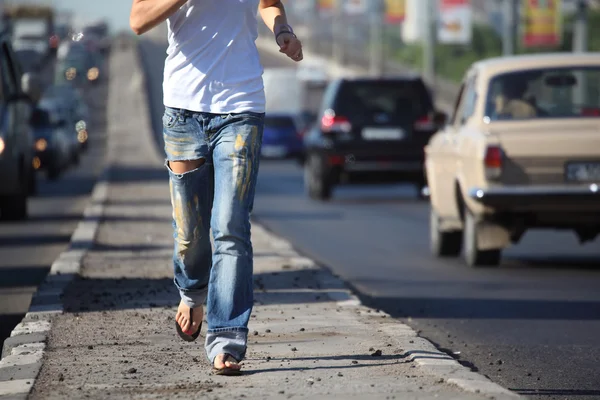 Mädchen läuft mitten in der Stadt auf Autobahn, Sicht ohne Kopf — Stockfoto