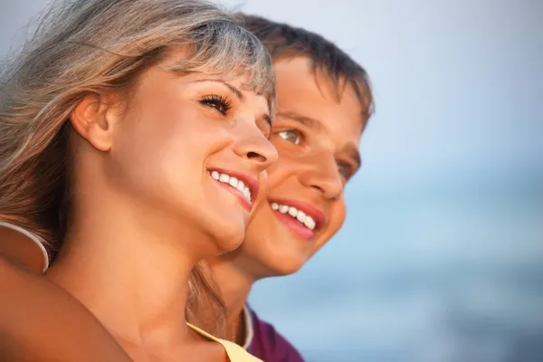 Niño sonriente y mujer joven en la playa por la noche, mirando a lo lejos — Foto de Stock