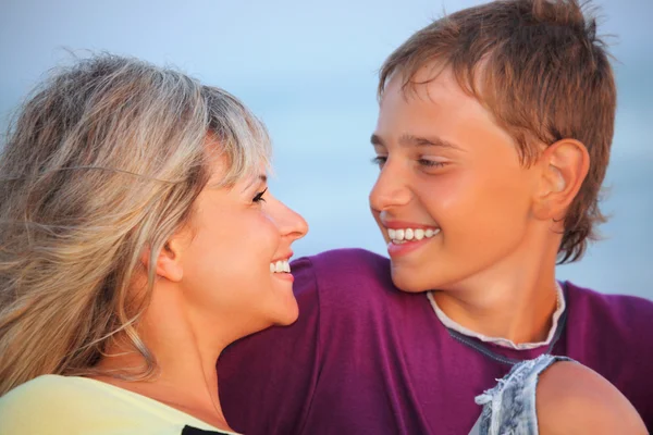 Усміхнений хлопчик і молода жінка на пляжі ввечері, дивлячись на — стокове фото