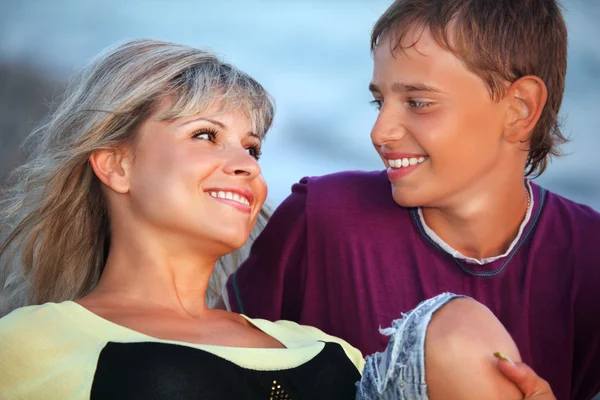 Garçon et jeune femme souriants sur la plage le soir, Regardant en face — Photo