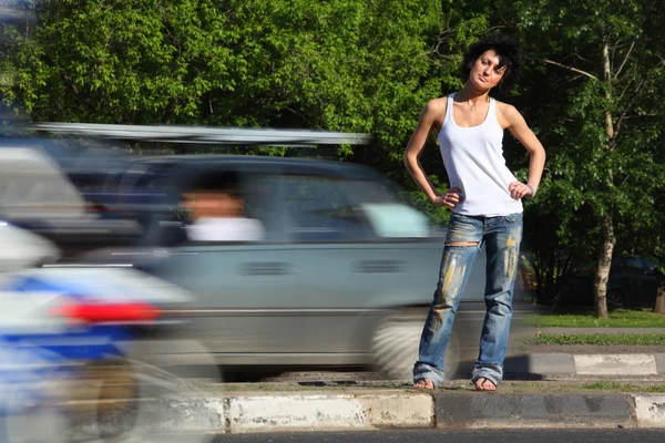 Menina fica na estrada entre carros — Fotografia de Stock