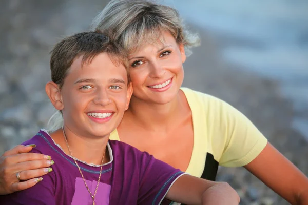 Uśmiechnięty chłopiec i młoda kobieta na plaży wieczorem — Zdjęcie stockowe