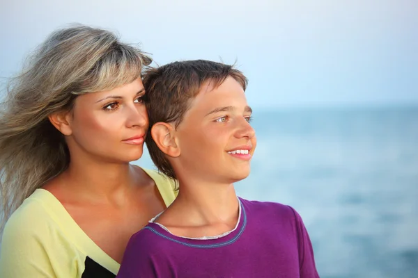 Uśmiechnięty chłopiec i młoda kobieta na plaży wieczorem, patrząc z daleka — Zdjęcie stockowe