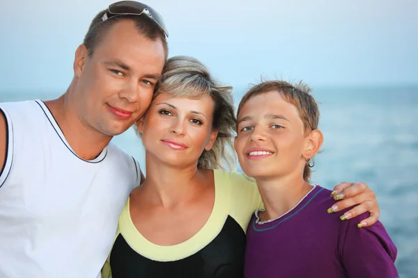 Familia feliz con niño sonriente en la playa por la noche — Foto de Stock