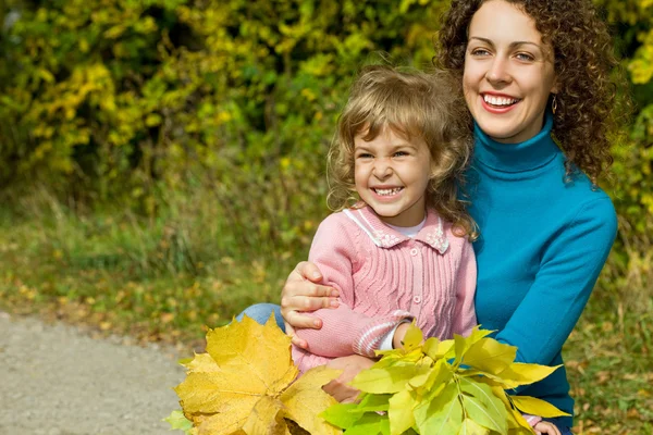 年轻女人和小女孩笑用叶子在花园里的手中 — 图库照片