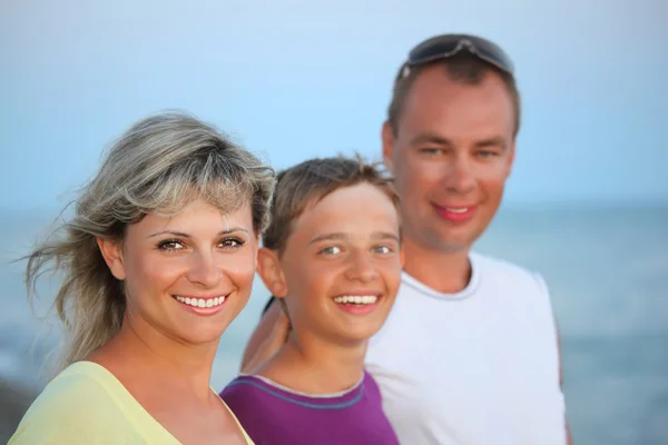 Счастливая семья с улыбчивым мальчиком на пляже вечером — стоковое фото
