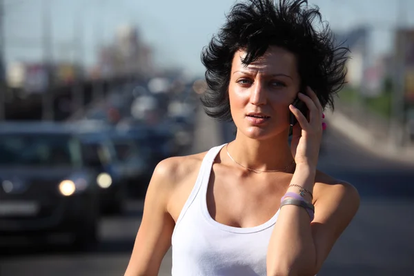 Lány beszél telefonon autópálya közepén, a város — Stock Fotó
