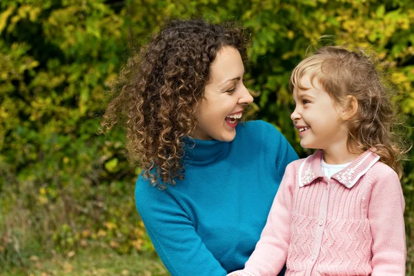 Young woman and little girl laugh in garden — Stock Photo, Image