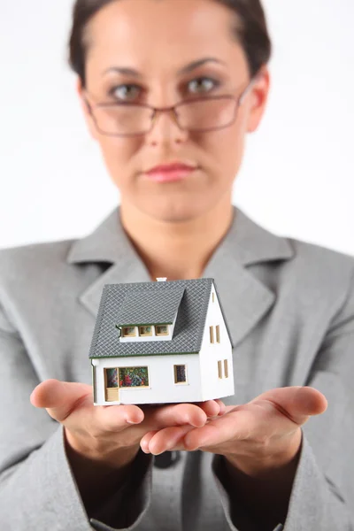 Business woman in glasses holds model of house — Stock Photo, Image