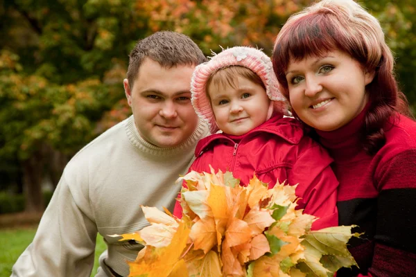 Happy family of three persons in the autumn park — Stock Photo, Image