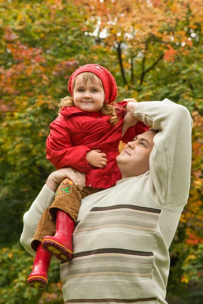 Liten flicka sitter på axeln på man I parken på hösten — Stockfoto