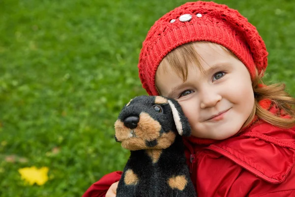 Little girl with a toy dog in park — Stock Photo, Image