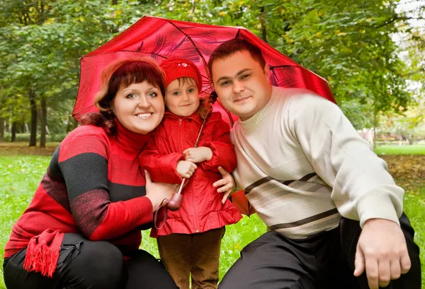 Married couple and little girl with umbrella in park — Stock Photo, Image