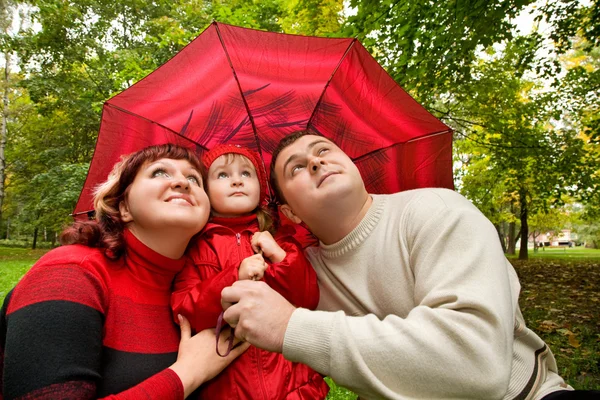 Married couple and little girl with umbrella in park — Stock Photo, Image