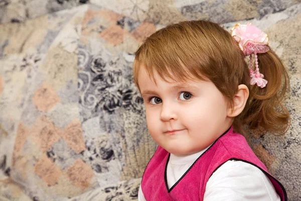 Bambina si siede su un divano in una stanza accogliente — Foto Stock