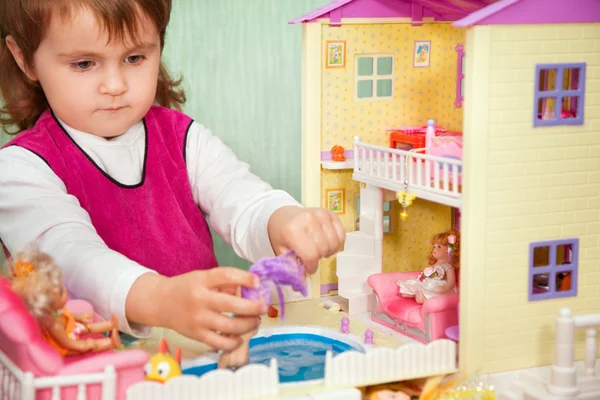 Маленька дівчинка миє ляльку в басейні іграшкового будинку — стокове фото