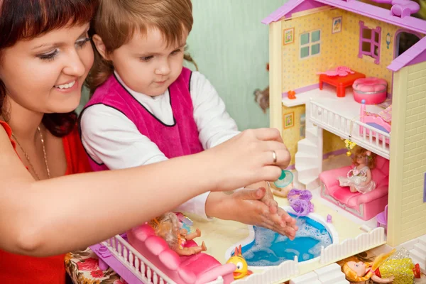 小さな女の子と女性のおもちゃの家のプールで人形を洗う — ストック写真