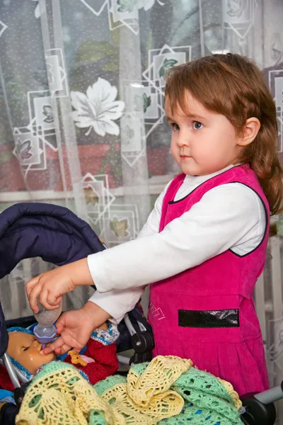 Маленька дівчинка годує ляльку в кареті — стокове фото