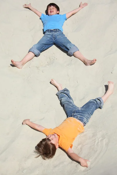 躺在沙子上的两个孩子 — 图库照片