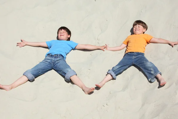 Dwoje dzieci leżące w pobliżu na piasku — Zdjęcie stockowe
