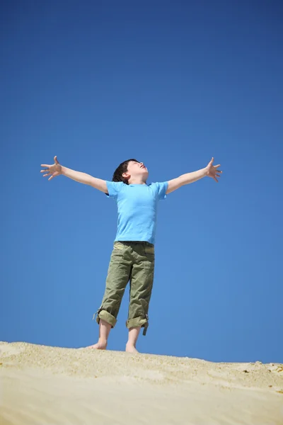 Boy stands on sand and looks upwards — Stock Photo, Image