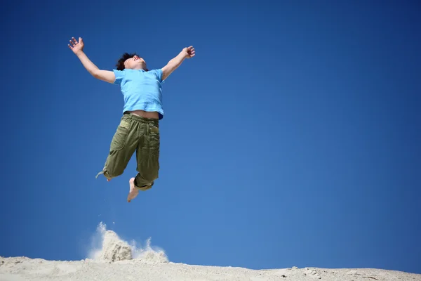 Boy jumps on sand with lifted hands — Stock Photo, Image
