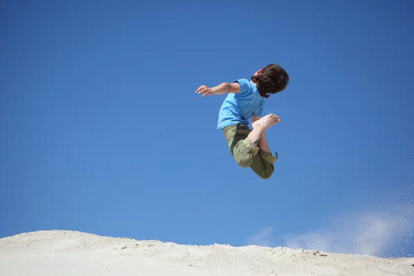 Chlapec skočí na písku — Stock fotografie