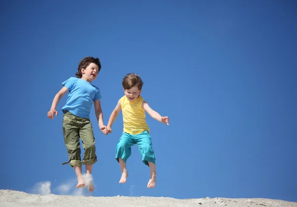 Iki çocuk kum üzerine atlamak — Stok fotoğraf