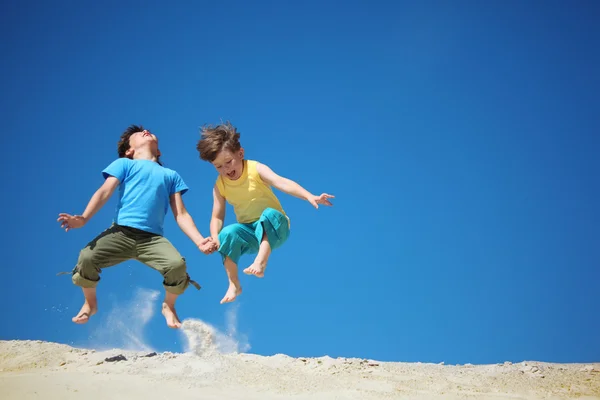 Iki çocuk kum üzerine atlamak — Stok fotoğraf