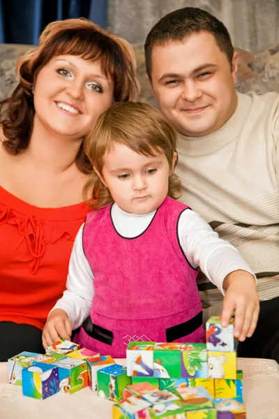 Coppia sposata e bambina che gioca a cubi in una stanza accogliente — Foto Stock