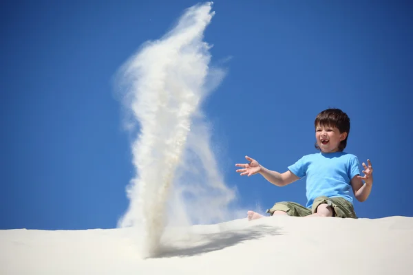 Boy sits on sand and scatters it — Stock Photo, Image